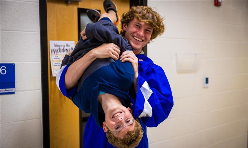 A senior and his younger brother smile